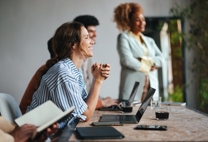 Møte med flere deltakere. Kvinne smiler.