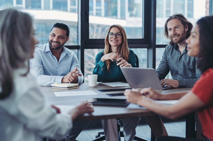 Deltakere smiler i et møte.